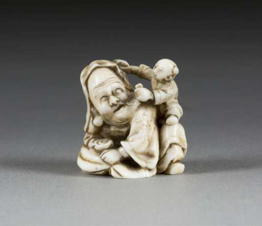 NETSUKE MIT DARSTELLUNG EINES ALTEN MANNES MIT KIND - Foto 1