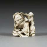 NETSUKE MIT DARSTELLUNG EINES ALTEN MANNES MIT KIND - Foto 1