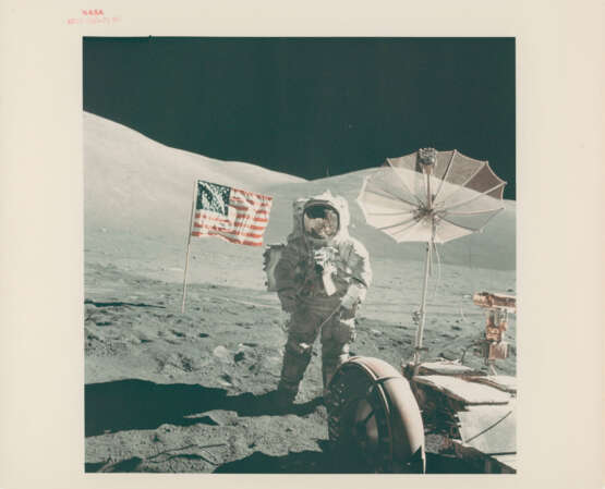Portrait of Harrison Schmitt with the reflection of the photographer in his visor; the Rover and the US flag from the LM window, December 7-19, 1972, EVA 3 and post EVA 2 - photo 1