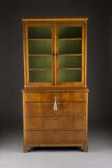 BIEDERMEIER-AUFSATZVITRINENSCHRANK Deutsch, um 1815/ 1820. Kirsche, furniert. H. 204,5 cm, B. 102 cm, T. 48 cm. Über vier Klotzfüßen gerader, vierschübiger Unterbau mit zweitürigem, verglastem Aufsatz. Rest., Furnierschäden.