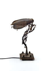 Wrought iron table lamp depicting an insect landing on a flower