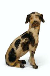 A CARVED AND PAINT-DECORATED PINE FIGURE OF A SITTING DOG