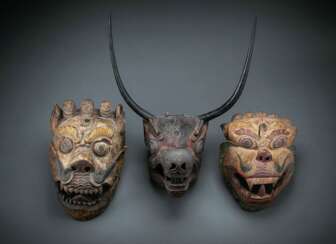 Drei gefasste Masken aus Holz, darunter Dämonenmaske und Maske mit langen Hörnern