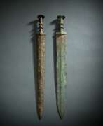 Dynastie des Zhou de l'Est. Zwei Schwerter aus Bronze, partiell grün korrodiert, Holzstände