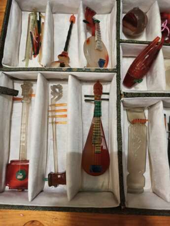 Satz von 26 Miniatur-Musikinstrumenten aus verschiedenen Steinen wie Achat und Malachit gearbeitet, Holzstände, Stoffbox - photo 2
