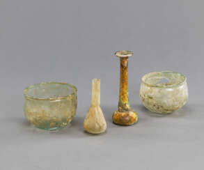 Vier antike Glasgefäße aus grünlichem Glas, teils versintert. Darunter zwei Balsamarien und zwei kleine Schalen