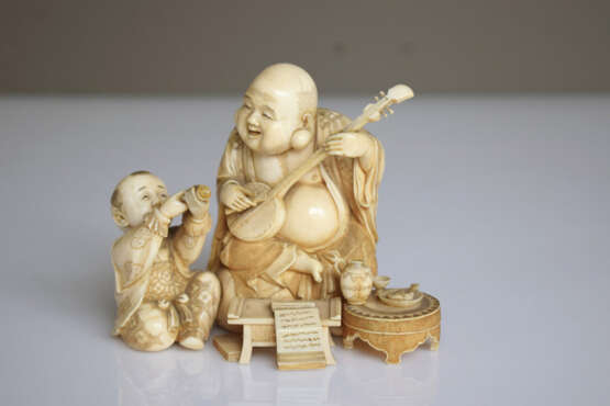 Feines Okimono aus Elfenbein mit Darstellung des musizierenden Hoteis nebst Trompete spielendem Karako - фото 2