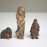 Vier Netsuke aus Holz: Hotei, Kwanju, Maske der Okame und Sennin mit Resten von polychromer Fassung - фото 2