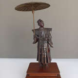 Bronze eines Höflings im Schatten seines aufgespannten Schirm s seinen Blick in die Ferne schweifend lassen - фото 2