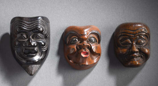 Drei Masken-Netsuke von Hyottoko, Okina und eines Greisen aus verschiedenen Hölzern, teilweise lackiert - фото 1