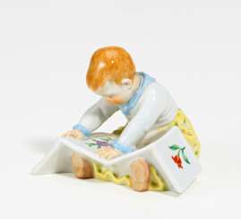 Porcelain figurine of child with picture-book