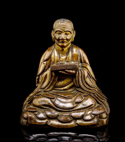 Bronze des Arhat Gopaka mit einem Buch sitzend auf einem doppelten Kissen dargestellt - фото 1