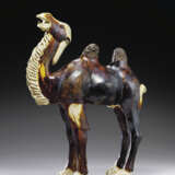 A CHESTNUT AND STRAW-GLAZED POTTERY FIGURE OF A BACTRIAN CAMEL - фото 1