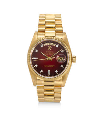 ROLEX, REF. 18038, DAY DATE, AN 18K YELLOW GOLD WRISTWATCH ON BRACELET WITH OXBLOOD VIGNETTE DIAL AND DIAMOND HOUR MARKERS - Foto 1