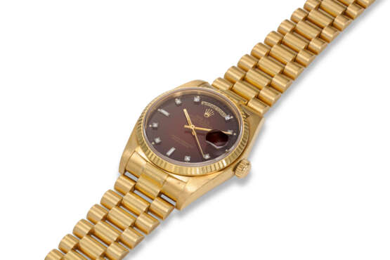 ROLEX, REF. 18038, DAY DATE, AN 18K YELLOW GOLD WRISTWATCH ON BRACELET WITH OXBLOOD VIGNETTE DIAL AND DIAMOND HOUR MARKERS - Foto 2