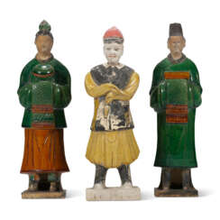 A YELLOW-GLAZED POTTERY FIGURE AND TWO GREEN AND AMBER-GLAZED POTTERY FIGURES OF ATTENDANTS