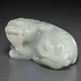 A FINELY CARVED PALE GREYISH-WHITE JADE FIGURE OF A RECUMBENT MYTHICAL BEAST - photo 1