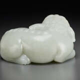 A FINELY CARVED PALE GREYISH-WHITE JADE FIGURE OF A RECUMBENT MYTHICAL BEAST - Foto 2