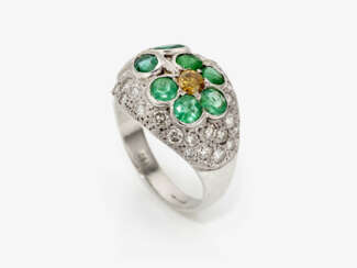 An unique floral cocktail ring decorated with emeralds, a yellow brilliant cut diamond and white brilliant cut diamonds