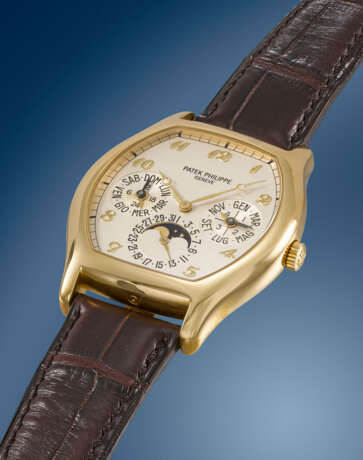PATEK PHILIPPE. A RARE AND ELEGANT 18K GOLD TONNEAU-SHAPED AUTOMATIC PERPETUAL CALENDAR WRISTWATCH WITH MOON PHASES, 24 HOUR, LEAP YEAR INDICATION, ADDITIONAL CASE BACK, CERTIFICATE OF ORIGIN AND BOX - photo 2