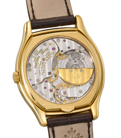 PATEK PHILIPPE. A RARE AND ELEGANT 18K GOLD TONNEAU-SHAPED AUTOMATIC PERPETUAL CALENDAR WRISTWATCH WITH MOON PHASES, 24 HOUR, LEAP YEAR INDICATION, ADDITIONAL CASE BACK, CERTIFICATE OF ORIGIN AND BOX - photo 3