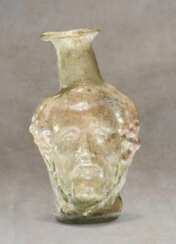 A ROMAN GREEN GLASS HEAD FLASK