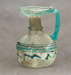 A LATE ROMAN PALE GREEN GLASS JUG WITH SPIRAL AND ZIGZAG TRAILING