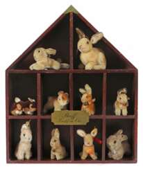 Diorama mit 9 Hasen und 2 Wollminis Steiff, Holzschaukasten in Form eines Hauses mit 10 offenen Fächern