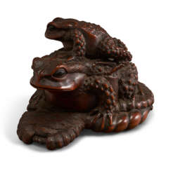 A CARVED WOOD SCULPTURE OF A BABY AND LARGE TOAD ON STRAW SANDAL