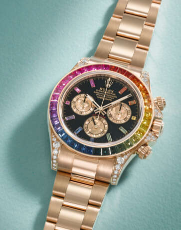 ROLEX. A RARE AND IMPRESSIVE 18K PINK GOLD, DIAMOND AND MULTI-COLOURED SAPPHIRE-SET AUTOMATIC CHRONOGRAPH WRISTWATCH WITH BRACELET - Foto 2