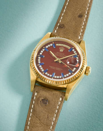 ROLEX. A RARE AND HIGHLY ATTRACTIVE 18K GOLD, DIAMOND AND SAPPHIRE-SET AUTOMATIC WRISTWATCH WITH SWEEP CENTRE SECONDS, DAY, DATE AND OXBLOOD LACQUERED `STELLA` DIAL - Foto 2