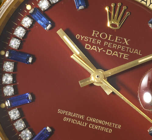 ROLEX. A RARE AND HIGHLY ATTRACTIVE 18K GOLD, DIAMOND AND SAPPHIRE-SET AUTOMATIC WRISTWATCH WITH SWEEP CENTRE SECONDS, DAY, DATE AND OXBLOOD LACQUERED `STELLA` DIAL - Foto 3
