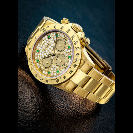 ROLEX. A RARE 18K GOLD, EMERALD AND DIAMOND-SET AUTOMATIC CHRONOGRAPH WRISTWATCH WITH BRACELET - photo 1