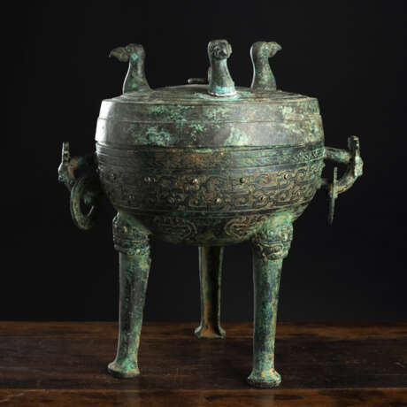 Archaistisches Deckelgefäß aus Bronze mit maskenförmigen Handhaben und Vogelkopfornamenten - Foto 1