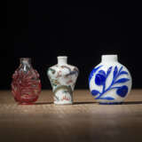 Zwei Snuffbottles aus Pekingglas mit rotem und blauem Überfang und eine Porzellansnuffbottle mit polychromem Drachendekor - Foto 1
