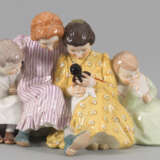 Vier Kinder beim Betrachten einer Puppe - Foto 1