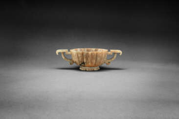 A MOTTLED BROWN JADE TWO-HANDLED BRACKET-LOBED CUP