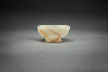 A RARE BEIGE AND RUSSET JADE FOOTED CUP