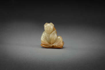 A YELLOW AND RUSSET JADE CARVING OF A BOY AND LOTUS