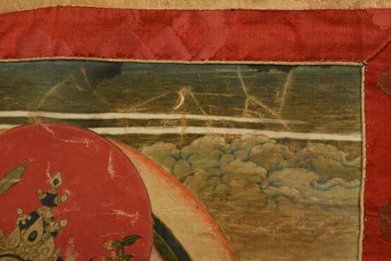 Tibetischer Thangka „Vierarmiger Caturbhuja Manjushri“ mit Schwert, Pfeil und Bogen, Lotosblüte und Buch, im Lotossitz, darunter zwei Lamas, 33x23,5cm (65x46cm mit Stoffrahmung), Altersspuren - photo 5