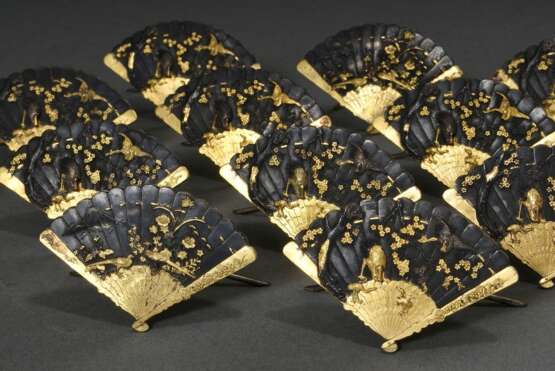 12 Japanische Shakudō Tischkartenhalter in "Fächer" Form mit verschiedenen, partiell vergoldeten und versilberten Reliefmotiven "Kraniche" und "Fasane", Meiji Periode, um 1900, 4,5x7,5cm, leichte Altersspuren, etw. berieben - Foto 1