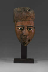 AN EGYPTIAN GLASS, BONE AND BRONZE-INLAID WOOD FACE FROM A COFFIN
