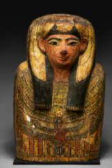 AN EGYPTIAN PAINTED WOOD, BRONZE, LIMESTONE AND GLASS UPPER PORTION OF A COFFIN LID