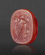 Cameo Glas. AN ETRUSCAN CARNELIAN SCARAB WITH A YOUTH WITH A STRIGIL