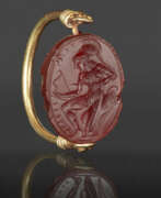 Cameo glass. A GREEK GOLD AND CARNELIAN SCARAB SWIVEL RING WITH AN AMAZON