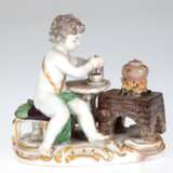Meissen-Figur "Allegorie- das Feuer", Putto am Herd sitzend und sich einen Kakao zubereitend, Nr. 697, 1. Hälfte 20. Jh., polychrom bemalt mit Goldstaffage, Rührstab bestoßen, 1. Wahl, H. 10,5 cm - фото 1