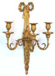 Wandleuchter, 3-armig, 19. Jh., Bronze feuervergoldet, in Form einer Fackel mit 3 Volutenarmen mit eingepaßten Tüllen, Leuchter mit Schleifenbekrönung, nachträgliche Bohrungen, H. 48 cm, B. 33 cm