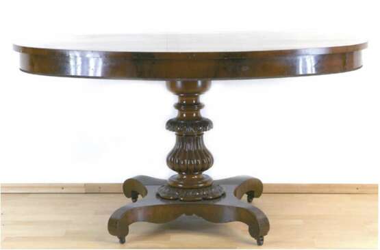 Biedermeier-Tisch, Mahagoni furniert, über 4-passig eingebogter Fußplatte auf Rollen gedrechselte, beschnitzte Mittelsäule und ovale Platte, restaurierungsbedürftig, 75x108x54 cm - photo 1
