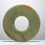 A SMOOTHLY POLISHED BI DISC WITH SHINY SURFACES CARVED FROM GREEN JADE WITH BROWN STRIPES - фото 1