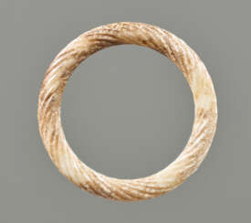 AN ORNAMENTAL RING IN PARTLY CALCIFIED WHITE JADE DECORATED WITH THE “TWISTED ROPE” PATTERN 
